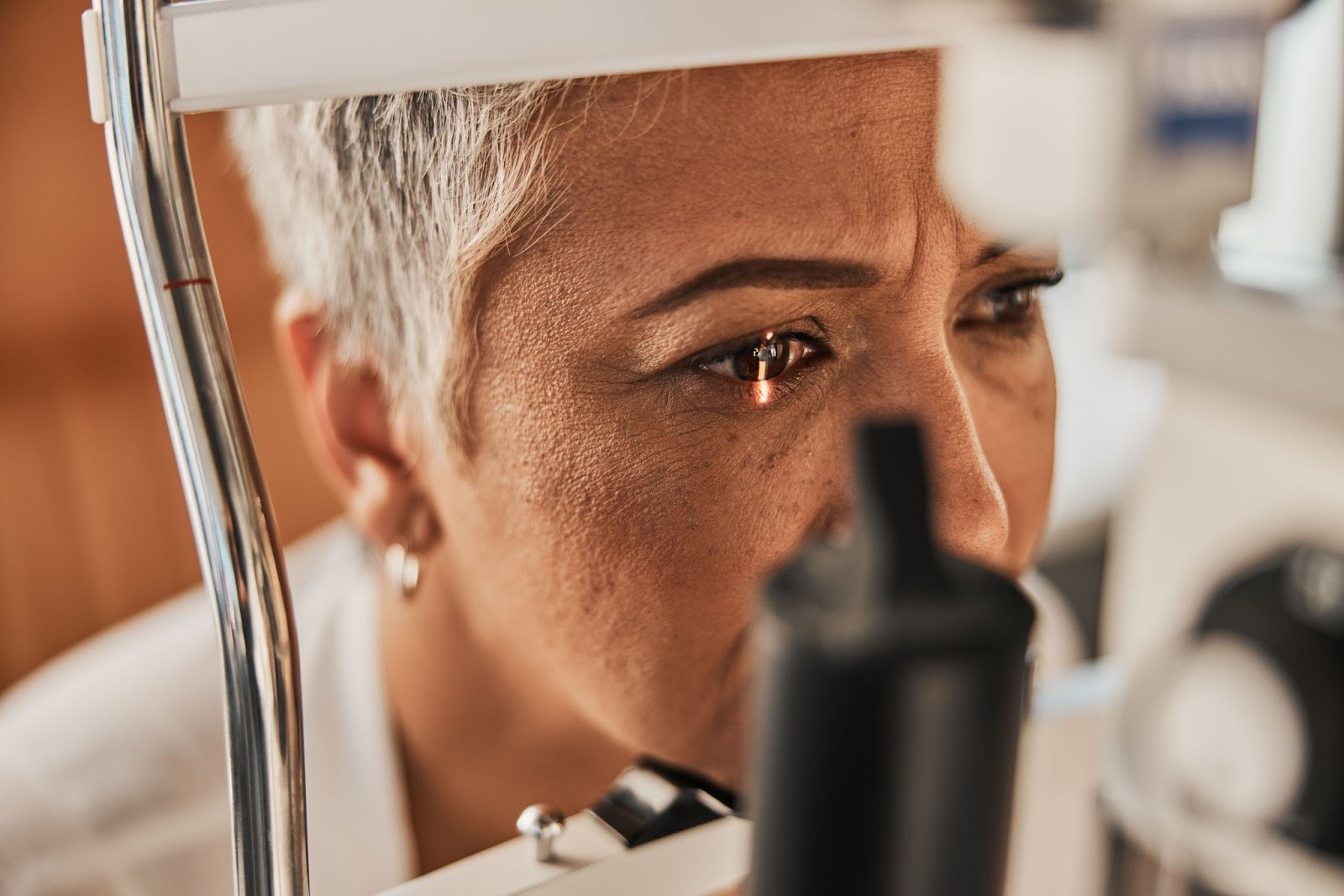 A mature patient undergoing a slit lamp examination to determine an accurate diagnosis for her eye condition.