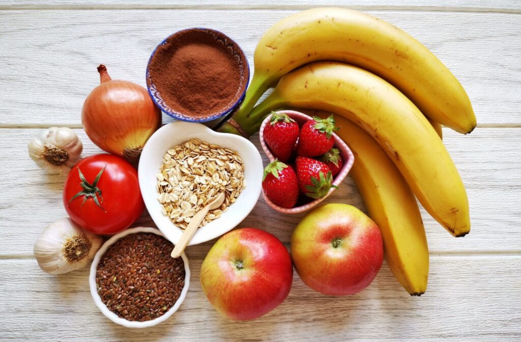 A variety of fruits, vegetables, oats, seeds, and other gut-friendly foods arranged on a wooden surface.
